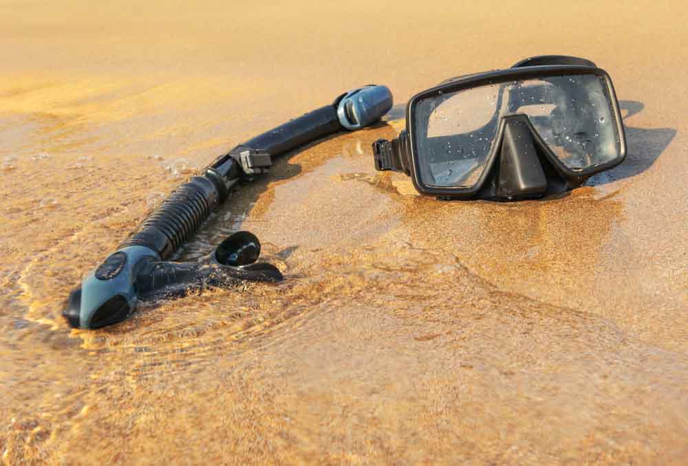52506452_sun-shining-to-black-snorkel-and-diving-mask-on-wet-beach-sand-washed-by-sea